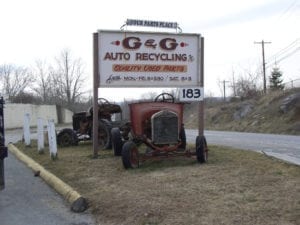 Company sign with old rusty cars underneath